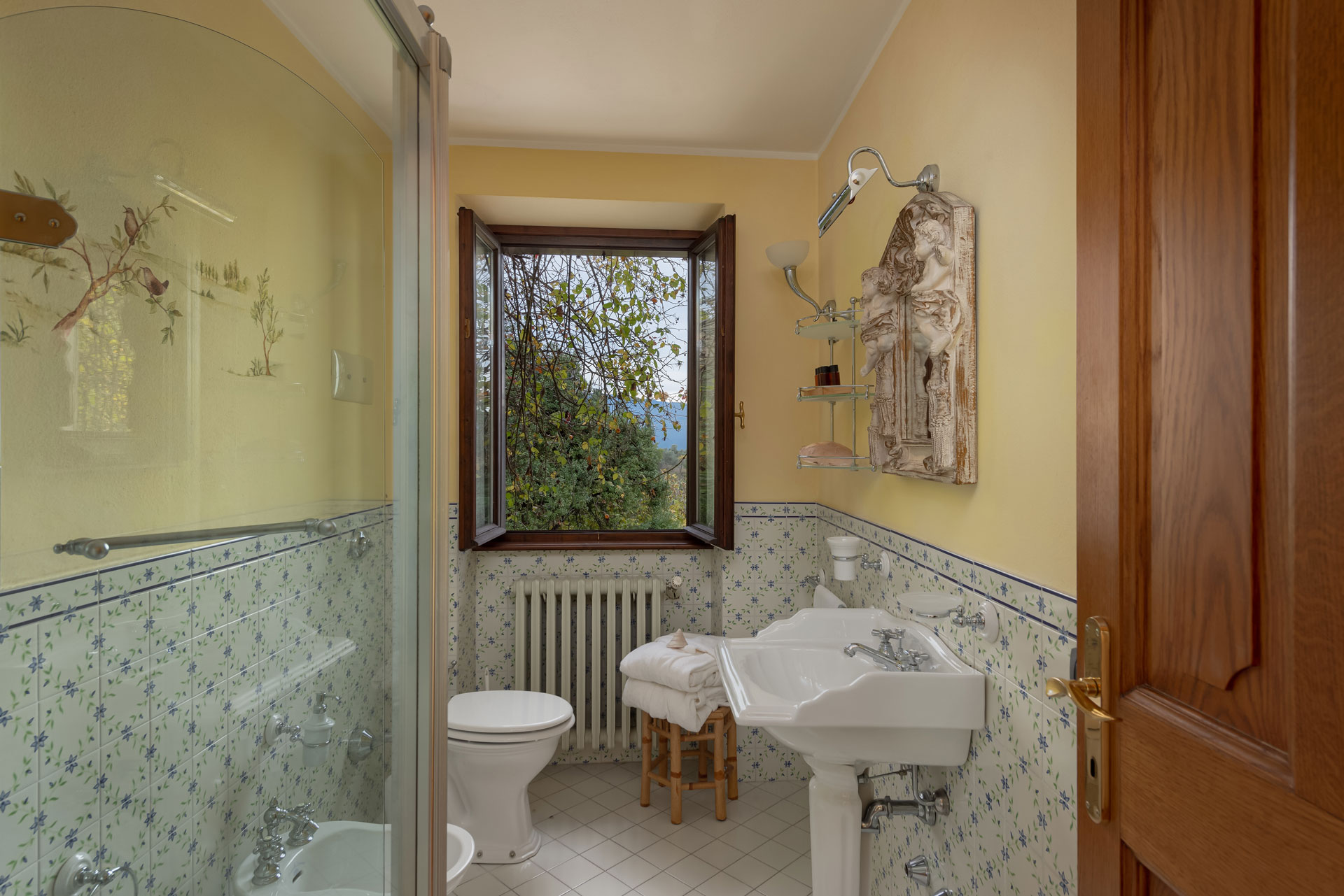 Bagno luminoso con decorazioni floreali e vista sul verde